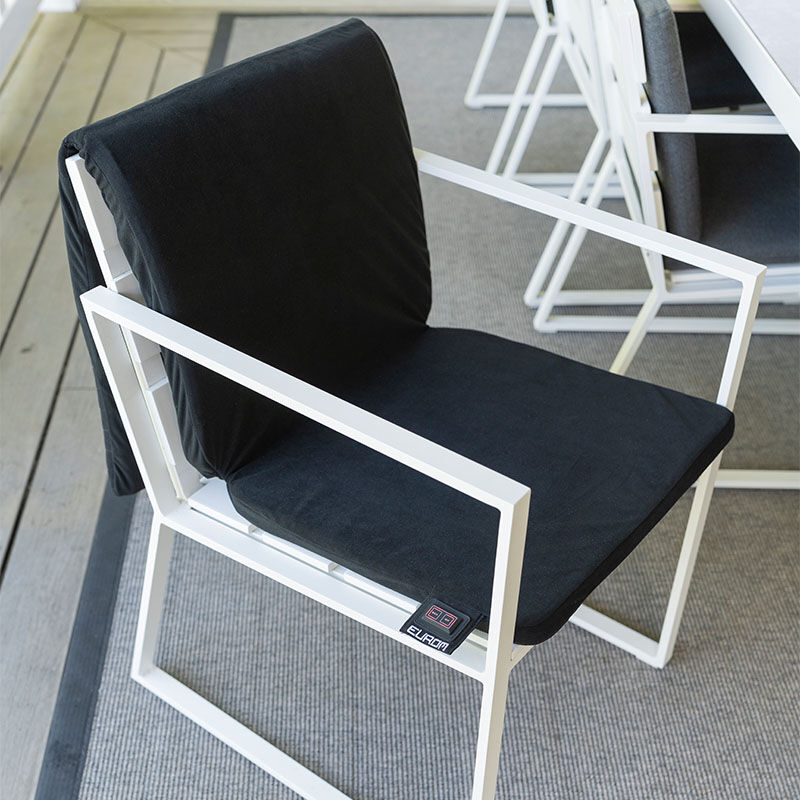 De Warmigo Dual Heatzone Draadloze Stoelverwarming ligt over een tuinstoel. 